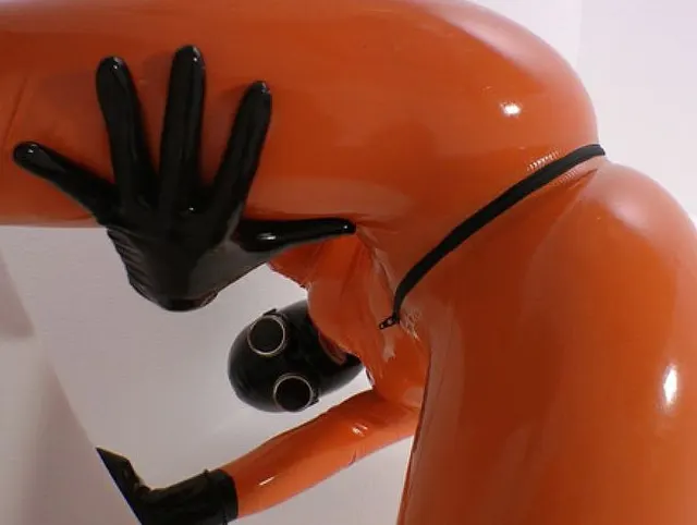 Pissen in orangen Latexcatsuit