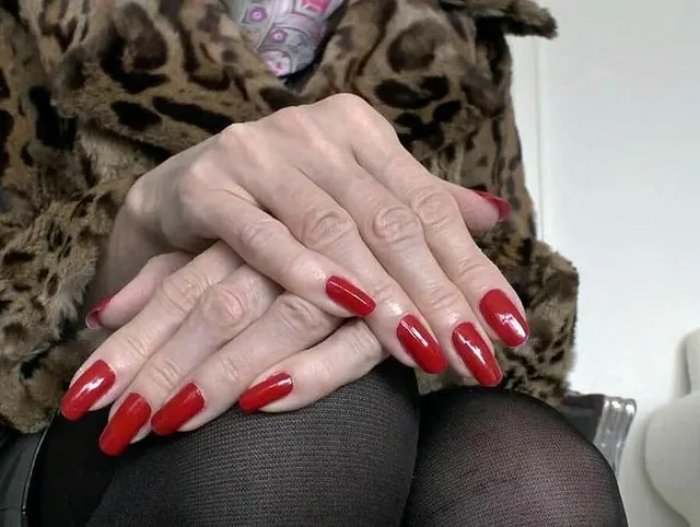 Rote Krallen Fingernägel und Pelzjacke